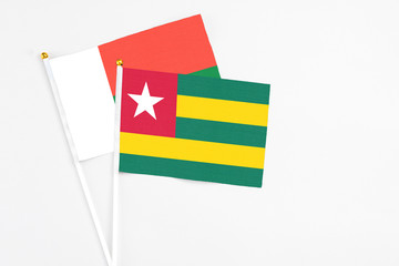 Togo and Madagascar stick flags on white background. High quality fabric, miniature national flag. Peaceful global concept.White floor for copy space.