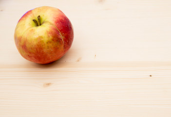 One ripe bright Apple on a wooden background.