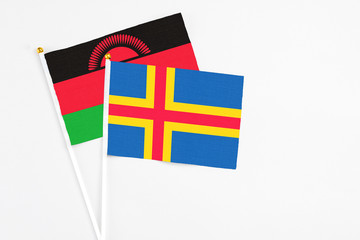 Aland Islands and Malawi stick flags on white background. High quality fabric, miniature national flag. Peaceful global concept.White floor for copy space.