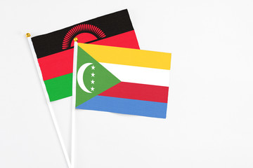 Comoros and Malawi stick flags on white background. High quality fabric, miniature national flag. Peaceful global concept.White floor for copy space.