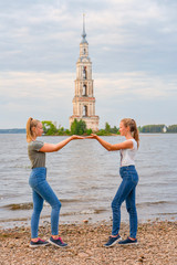 2 junge Teenanger Mädchen halten den Kalyazin Glockenturm in ihren Händen