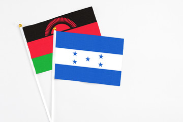 Honduras and Malawi stick flags on white background. High quality fabric, miniature national flag. Peaceful global concept.White floor for copy space.