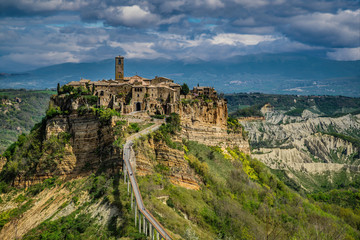 Fototapeta na wymiar Civita Bagnoregio Perched on top of a hill among the valleys formed by Chiaro and Torbido streams, Civita appears clinged to the edge of a cliff where it dominates the wide desolated valley 