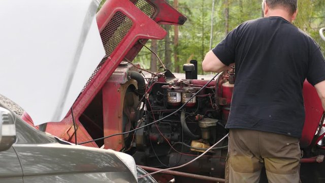 Static shot of a mechanic repairing an old tractor motor, on a sunny, summer day, in Ostrobothnia, Finland