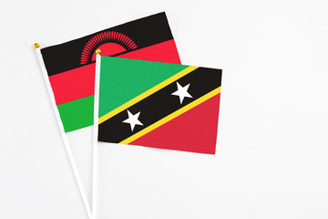 Saint Kitts And Nevis and Malawi stick flags on white background. High quality fabric, miniature national flag. Peaceful global concept.White floor for copy space.