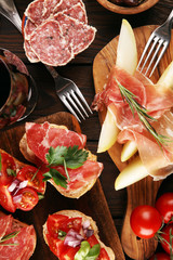 Italian antipasti wine snacks set. Cheese variety, Mediterranean olives, seafood salad, Prosciutto di Parma, tomatoes, anchovy and wine in glasses