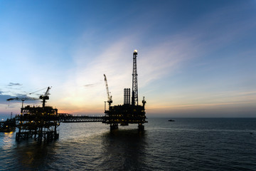 Fototapeta premium Silhouette of oil production platform during sunset