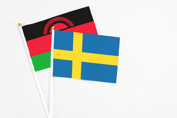 Sweden and Malawi stick flags on white background. High quality fabric, miniature national flag. Peaceful global concept.White floor for copy space.