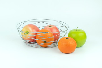 Apples and oranges in a decoratively wire basket put on isolated white background and there are an apple and oranges outside the wire basket with clipping path.