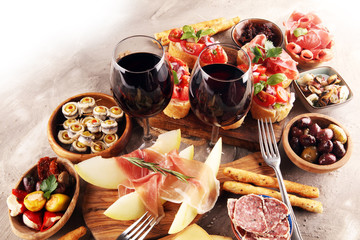 Italian antipasti wine snacks set. Cheese variety, Mediterranean olives, seafood salad, Prosciutto di Parma, tomatoes, anchovy and wine in glasses