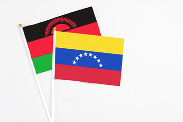 Venezuela and Malawi stick flags on white background. High quality fabric, miniature national flag. Peaceful global concept.White floor for copy space.