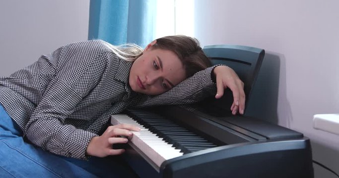 Upset teenage girl playing piano at home