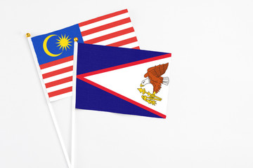American Samoa and Malaysia stick flags on white background. High quality fabric, miniature national flag. Peaceful global concept.White floor for copy space.