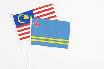 Aruba and Malaysia stick flags on white background. High quality fabric, miniature national flag. Peaceful global concept.White floor for copy space.