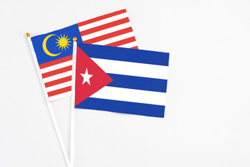 Cuba and Malaysia stick flags on white background. High quality fabric, miniature national flag. Peaceful global concept.White floor for copy space.