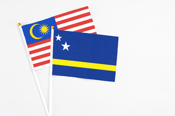 Curacao and Malaysia stick flags on white background. High quality fabric, miniature national flag. Peaceful global concept.White floor for copy space.