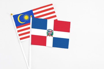 Dominican Republic and Malaysia stick flags on white background. High quality fabric, miniature national flag. Peaceful global concept.White floor for copy space.