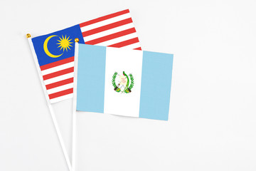 Obraz premium Guatemala and Malaysia stick flags on white background. High quality fabric, miniature national flag. Peaceful global concept.White floor for copy space.