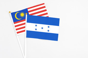 Honduras and Malaysia stick flags on white background. High quality fabric, miniature national flag. Peaceful global concept.White floor for copy space.