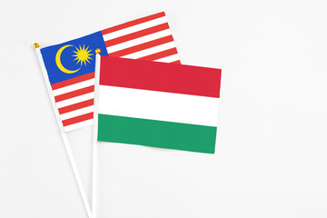 Hungary and Malaysia stick flags on white background. High quality fabric, miniature national flag. Peaceful global concept.White floor for copy space.