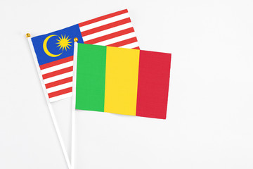Mali and Malaysia stick flags on white background. High quality fabric, miniature national flag. Peaceful global concept.White floor for copy space.