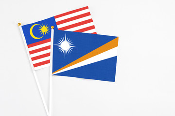 Marshall Islands and Malaysia stick flags on white background. High quality fabric, miniature national flag. Peaceful global concept.White floor for copy space.