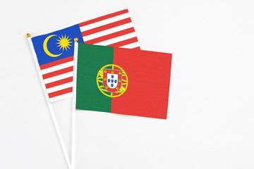 Portugal and Malaysia stick flags on white background. High quality fabric, miniature national flag. Peaceful global concept.White floor for copy space.