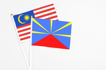 Reunion and Malaysia stick flags on white background. High quality fabric, miniature national flag. Peaceful global concept.White floor for copy space.