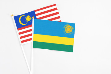 Rwanda and Malaysia stick flags on white background. High quality fabric, miniature national flag. Peaceful global concept.White floor for copy space.