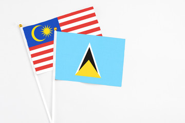 Saint Lucia and Malaysia stick flags on white background. High quality fabric, miniature national flag. Peaceful global concept.White floor for copy space.