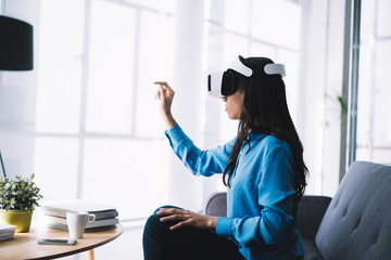 Woman with VR headset poking finger at virtual object