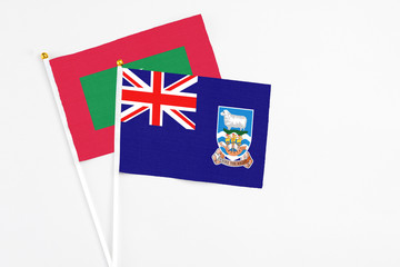 Fototapeta premium Falkland Islands and Maldives stick flags on white background. High quality fabric, miniature national flag. Peaceful global concept.White floor for copy space.