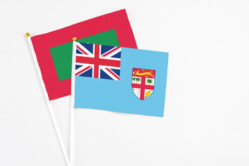 Fiji and Maldives stick flags on white background. High quality fabric, miniature national flag. Peaceful global concept.White floor for copy space.