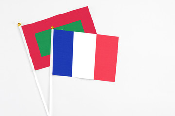 France and Maldives stick flags on white background. High quality fabric, miniature national flag. Peaceful global concept.White floor for copy space.