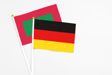 Germany and Maldives stick flags on white background. High quality fabric, miniature national flag. Peaceful global concept.White floor for copy space.