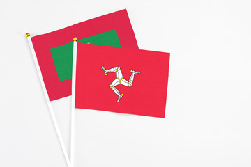 Isle Of Man and Maldives stick flags on white background. High quality fabric, miniature national flag. Peaceful global concept.White floor for copy space.