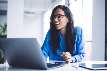 Black woman with wide smile working at laptop