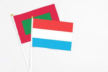 Luxembourg and Maldives stick flags on white background. High quality fabric, miniature national flag. Peaceful global concept.White floor for copy space.