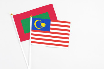 Malaysia and Maldives stick flags on white background. High quality fabric, miniature national flag. Peaceful global concept.White floor for copy space.