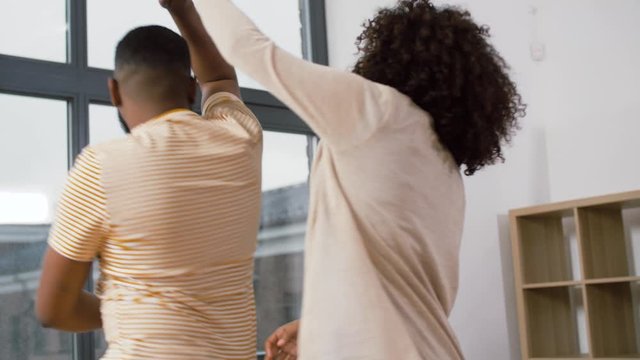 moving, repair and real estate concept - happy african american couple dancing at new home