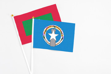 Northern Mariana Islands and Maldives stick flags on white background. High quality fabric, miniature national flag. Peaceful global concept.White floor for copy space.
