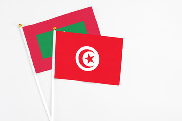 Tunisia and Maldives stick flags on white background. High quality fabric, miniature national flag. Peaceful global concept.White floor for copy space.