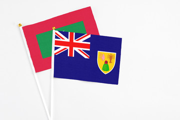Fototapeta premium Turks And Caicos Islands and Maldives stick flags on white background. High quality fabric, miniature national flag. Peaceful global concept.White floor for copy space.