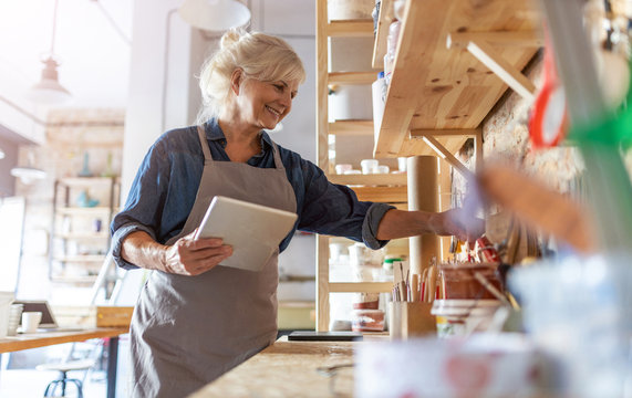 Senior craftswoman with tablet computer in art studio