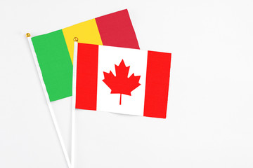 Canada and Mali stick flags on white background. High quality fabric, miniature national flag. Peaceful global concept.White floor for copy space.