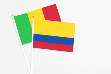 Colombia and Mali stick flags on white background. High quality fabric, miniature national flag. Peaceful global concept.White floor for copy space.