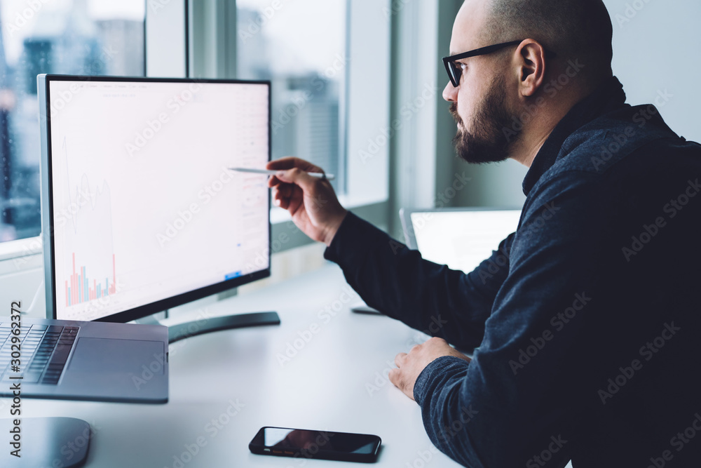 Wall mural man looking at graph on computer
