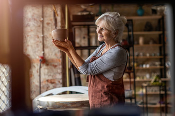 Senior woman pottery artist makes ceramics from clay