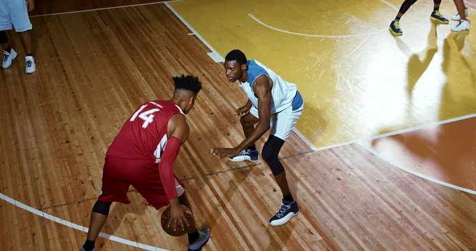 Professional basketball player in action performing slam dunk in a basketball hoop on a sports arena.