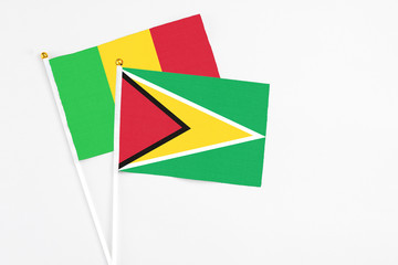 Guyana and Mali stick flags on white background. High quality fabric, miniature national flag. Peaceful global concept.White floor for copy space.